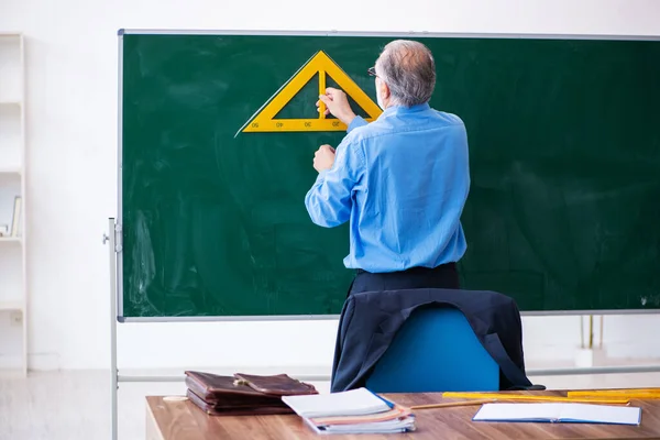Velho professor de geometria masculina segurando triângulo — Fotografia de Stock