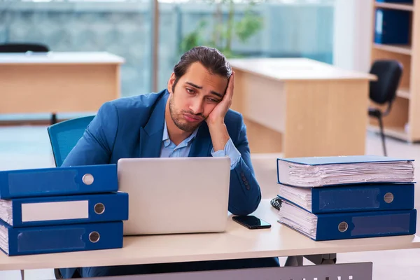 Ung manlig anställd och för mycket arbete på kontoret — Stockfoto