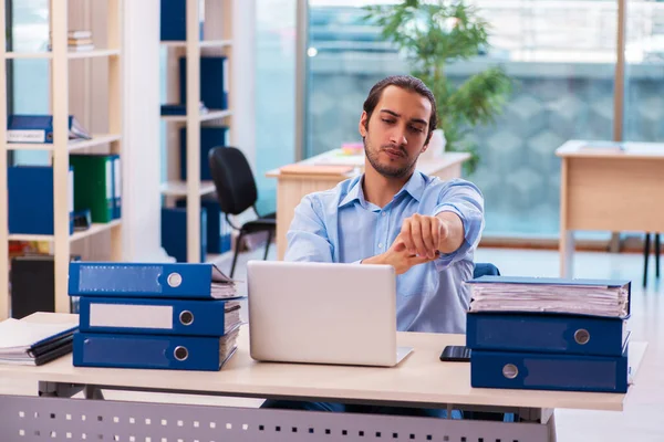 Ung manlig anställd och för mycket arbete på kontoret — Stockfoto