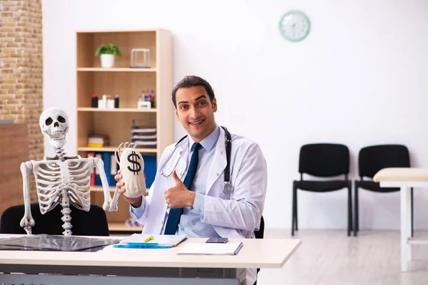 Young male doctor and skeleton patient in expensive medicine con — Stock Photo, Image