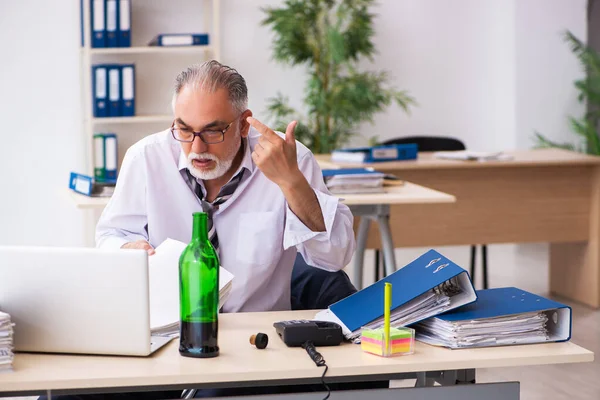 Starý muž zaměstnanec pití alkoholu v kanceláři — Stock fotografie