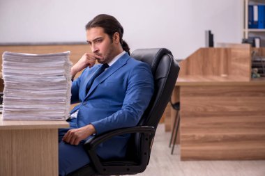 Ofisteki aşırı işten memnun olmayan genç bir erkek işçi.