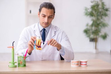Genç erkek doktor stomatolojist klinikte çalışıyor.