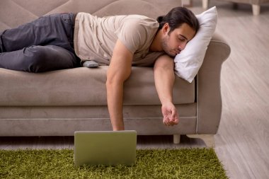 Evdeki kanepede yatan genç adam.