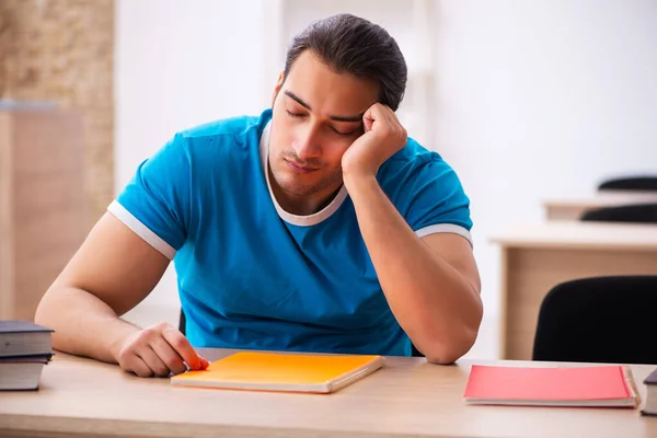 Studente maschio esausto che si prepara agli esami in classe — Foto Stock