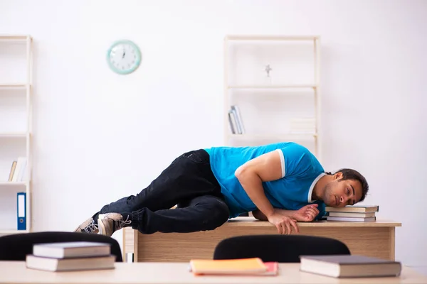 Exhausted male student preparing for the exams in the classroom — Stock Photo, Image