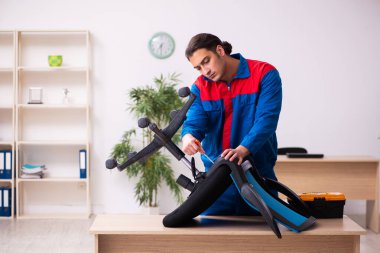 Genç erkek müteahhit ofiste mobilya tamir ediyor.