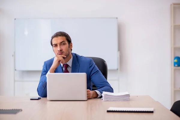 Mladý muž zaměstnanec sedí v kanceláři před tabulí — Stock fotografie