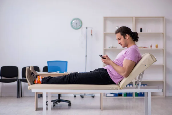 Νεαρός άνδρας ασθενής με smartphone περιμένει το γιατρό — Φωτογραφία Αρχείου
