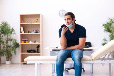 Genç adam hastanede salgın sırasında doktoru bekliyor.