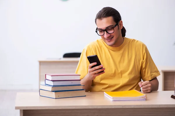 Mladý student drží mobilní telefon během přípravy zkoušky — Stock fotografie