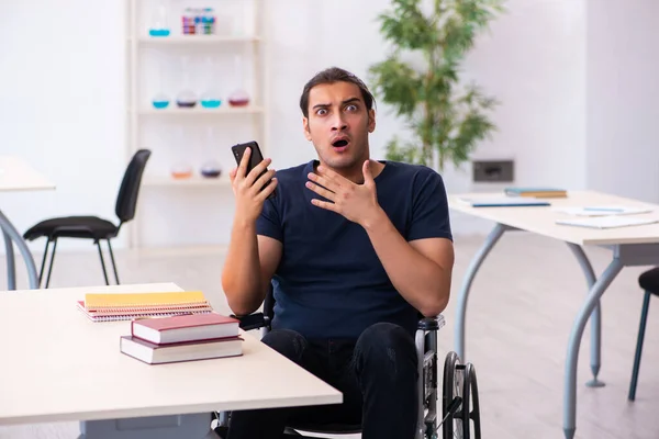 Joven estudiante masculino en silla de ruedas preparándose para los exámenes — Foto de Stock