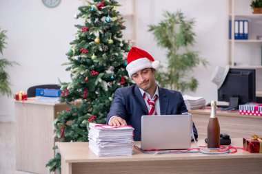 Genç erkek çalışan ofiste yeni yılı kutluyor.