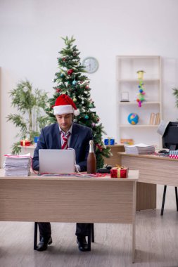 Genç erkek çalışan ofiste yeni yılı kutluyor.