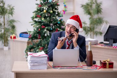 Genç erkek çalışan ofiste yeni yılı kutluyor.