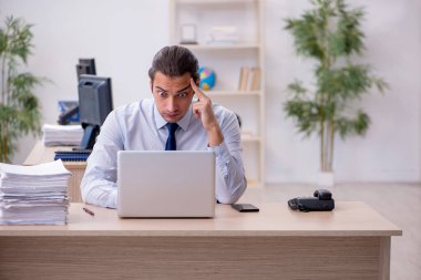 Genç erkek çalışan ofiste oturuyor.