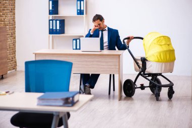 Genç erkek çalışan işyerinde çocuğa bakıyor.