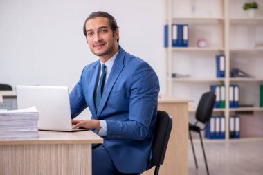 Genç bir erkek çalışan ve ofiste çok fazla iş var.