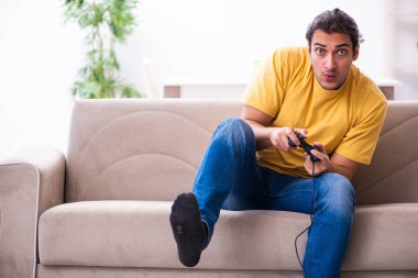 Genç adam evde joystick oynuyor.