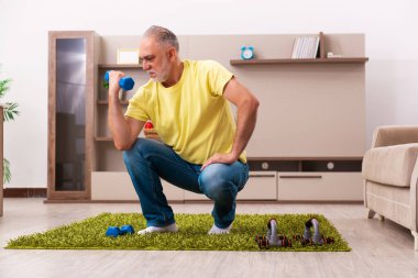 Yaşlı adam evde spor egzersizleri yapıyor.