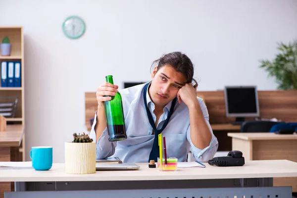 Ung manlig anställd dricker alkohol på arbetsplatsen — Stockfoto