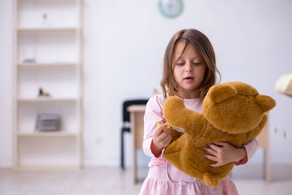 Маленькая девочка держит медвежью игрушку в ожидании врача в клинике