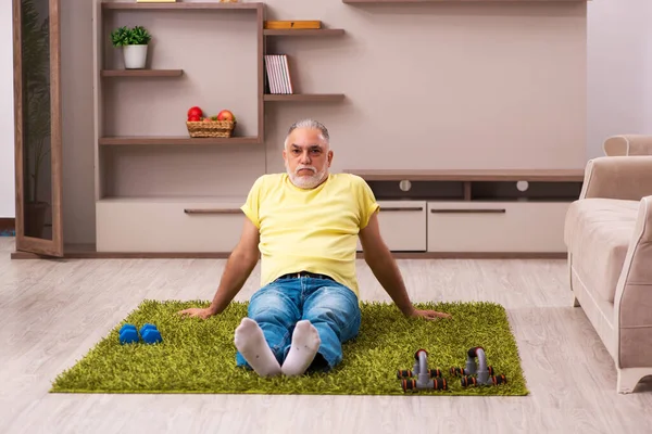 Hombre anciano haciendo ejercicios deportivos en casa — Foto de Stock