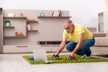 Yaşlı adam evde spor egzersizleri yapıyor.