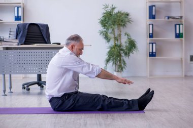 Mola sırasında fiziksel egzersiz yapan yaşlı bir erkek.