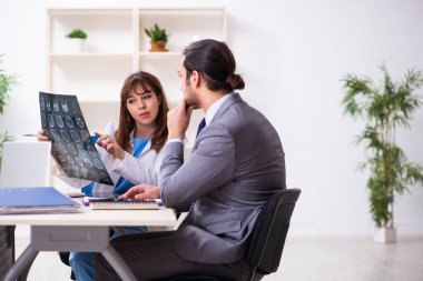 Genç bayan doktor ve hasta iş adamı ofiste.