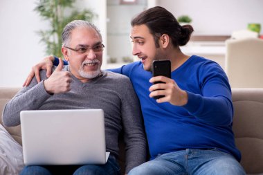 Baba oğul kanepede bilgisayar başında oturuyor.