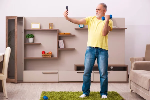 Verouderde man doet sport oefeningen thuis — Stockfoto