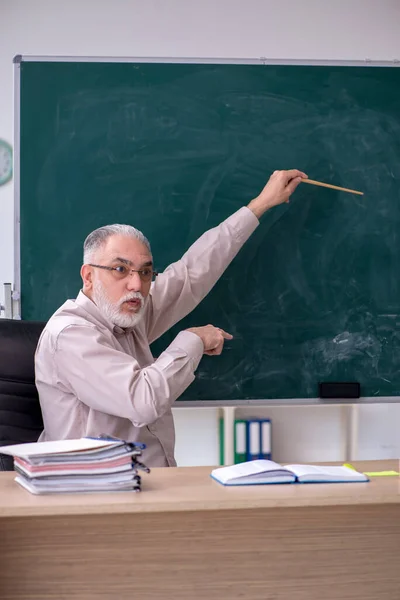 Oude mannelijke leraar zit in de klas — Stockfoto