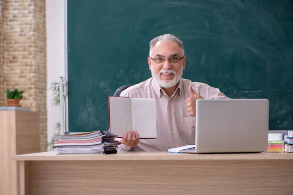 Vecchio insegnante di sesso maschile seduto in classe — Foto Stock