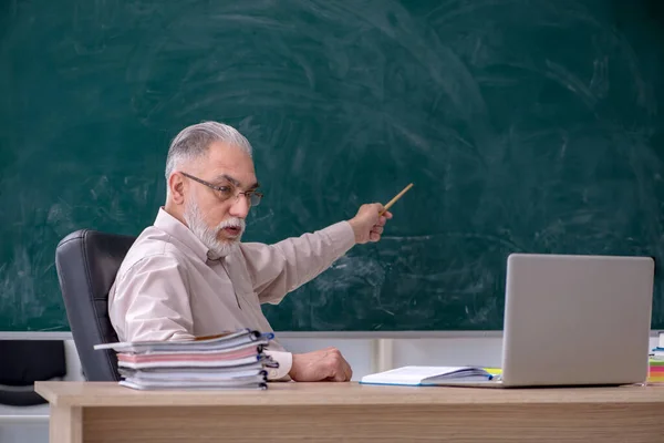 Oude mannelijke leraar zit in de klas — Stockfoto