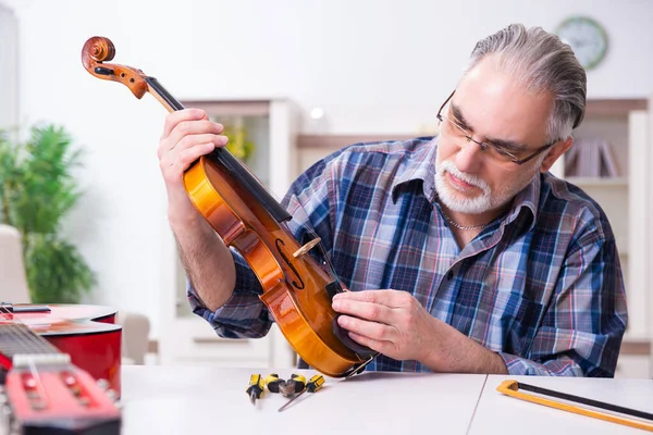 Réparateur masculin senior réparant des instruments de musique à la maison — Photo