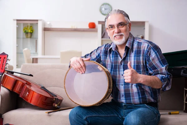 Hombre mayor reparador reparando instrumentos musicales en casa —  Fotos de Stock