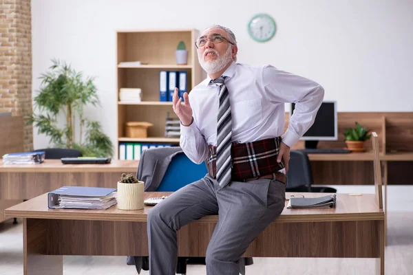 Old male employee suffering from radiculitis at workplace — Stock Photo, Image