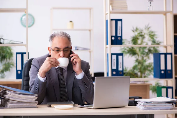 Alte männliche Angestellte trinkt Kaffee im Büro — Stockfoto