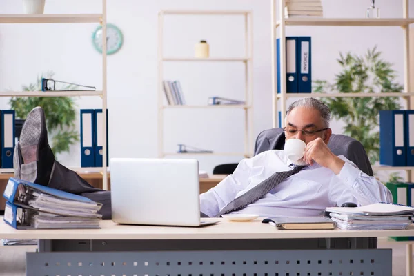 Un vieil employé boit du café au bureau — Photo