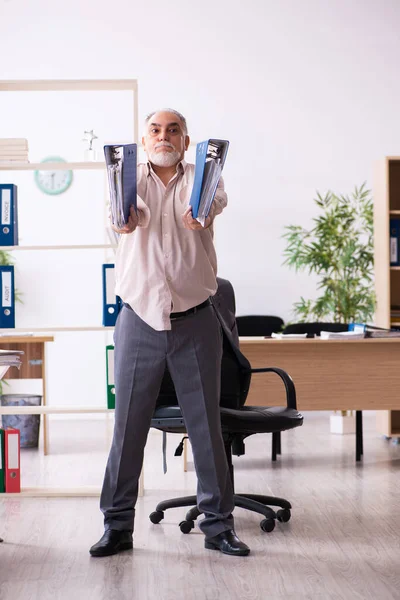 Старый работник мужского пола делает физические упражнения на рабочем месте — стоковое фото