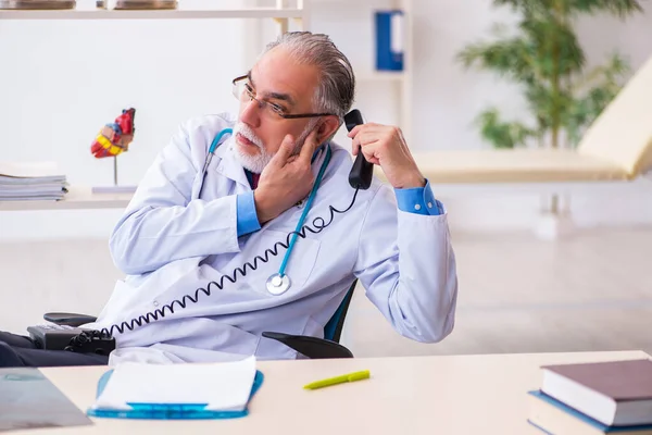 Yaşlı erkek doktor klinikte telefonla konuşuyor. — Stok fotoğraf