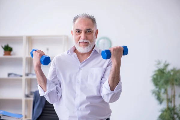 Åldrad manlig anställd som motionerar under pausen — Stockfoto