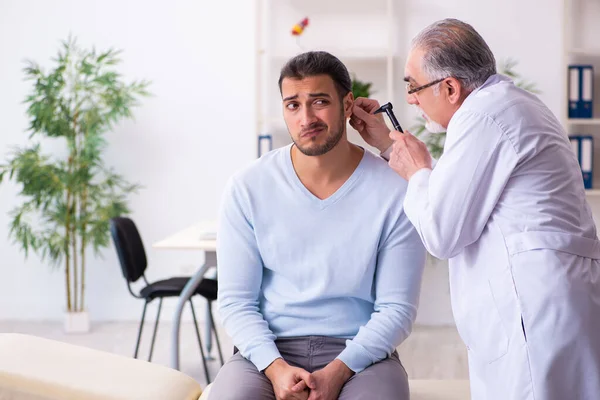 Jonge zieke man bezoekt oude arts otolaryngoloog — Stockfoto