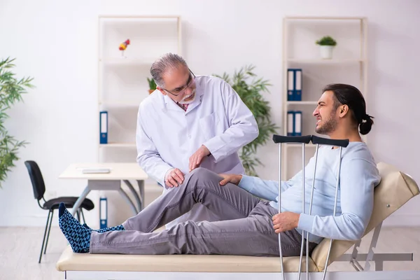 Unga ben skadad man besöker gammal läkare osteopat — Stockfoto