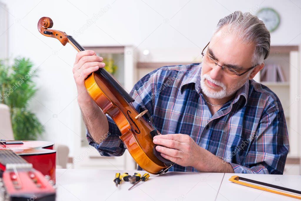 Senior male repairman repairing musical instruments at home