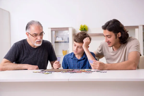 Three generations of family playing jigsaw puzzle game — Stock Photo, Image
