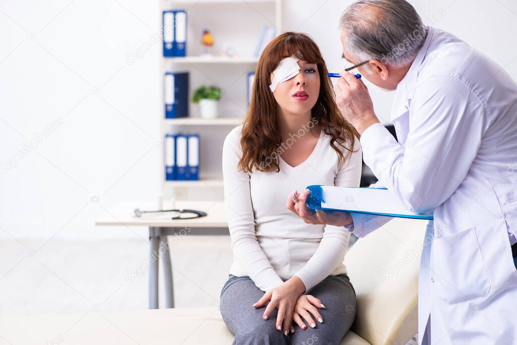 Young woman visiting old male doctor ophthalmologist