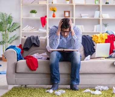 Genç adam dağınık bir odada çalışıyor.