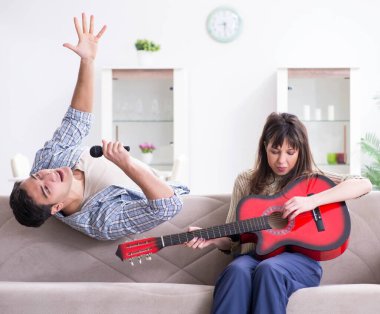 Genç bir aile evde şarkı söylüyor ve müzik çalıyor.